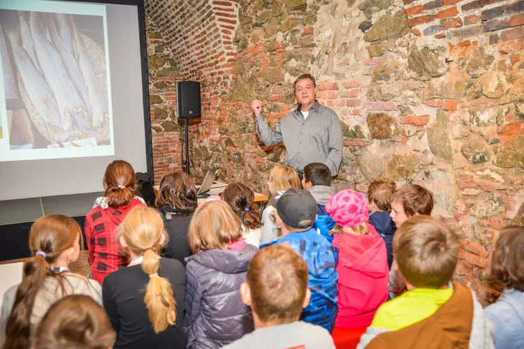 Wolfgang Neubauer holding a lecture at the children's university. The 'Kinderuni on tour' made a stop at the fascinating 'Viking' exhibition at Schallaburg Castle. At this event, schoolchildren can experiment at various research stations and attend their first lecture. The children listened with great interest to the archaeologist Wolfgang Neubauer, who presented exciting facts about the life of the Vikings.Credit: Markus Haslinger/APA-Fotoservice.